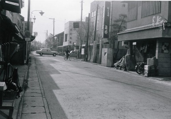 。大山街道を中央に据えた写真。奥の十字路には車が走っており、街道の両側には商店などの街並みが見える